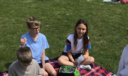 Some children enjoying their picnic lunch on the school field.
