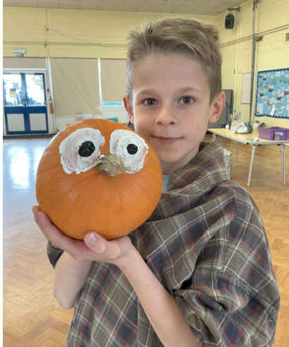 Child holding a painted pumpkin with eyes